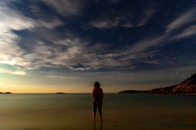 As the moon rises on Acadia National Park, Amanda stands in the chilly surf.