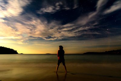 As the moon rises on Acadia National Park, Amanda stands in the chilly surf.